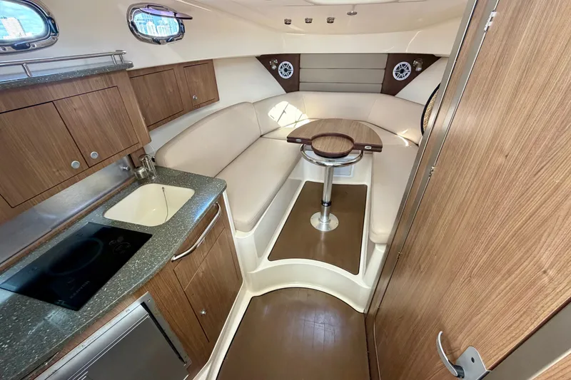 Slide: The Image of Interior of 2014 Boston Whaler 315 Conquest, featuring a cozy cabin with kitchenette and seating. - 44