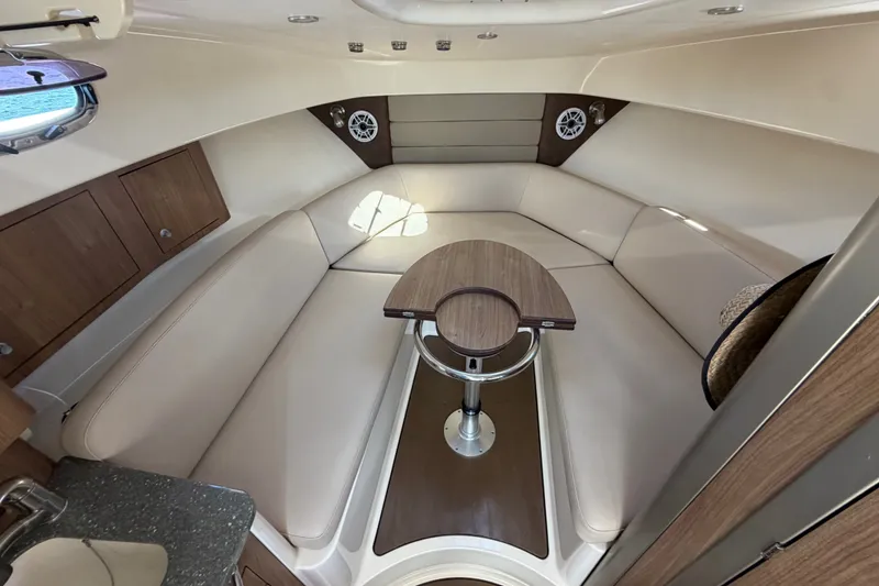 Slide: The Image of 2014 Boston Whaler 315 Conquest cabin interior with beige seating and wooden table. - 46