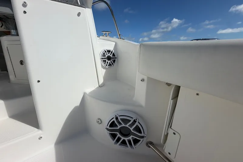 Slide: The Image of 2014 Boston Whaler 315 Conquest boat interior with speakers and seating under blue sky. - 21