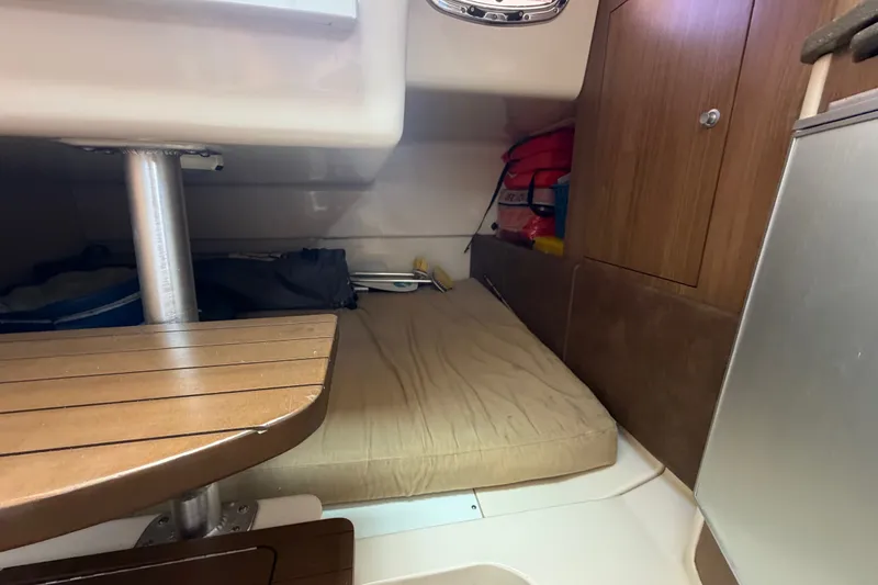 Slide: The Image of 2014 Boston Whaler 315 Conquest cabin interior with bed and wooden table. - 53
