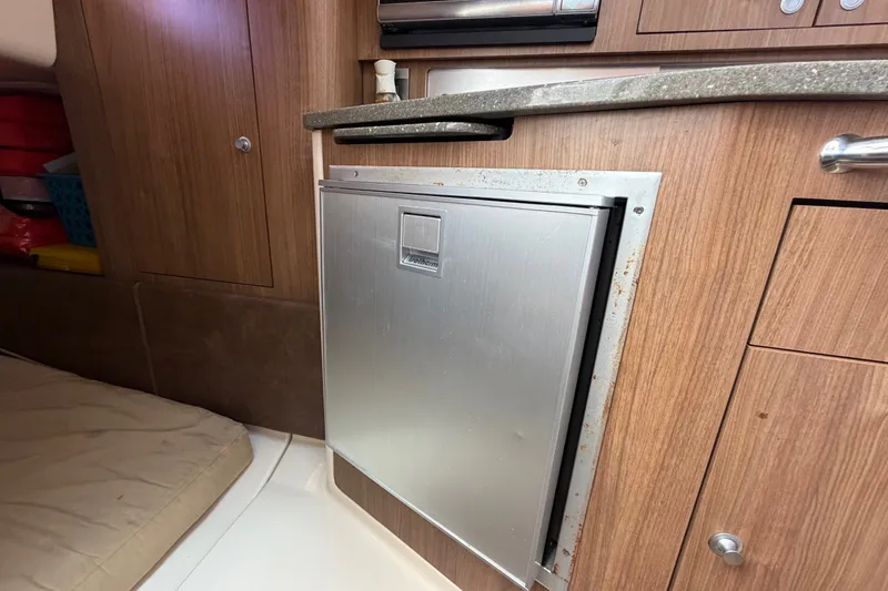 Slide: The Image of 2014 Boston Whaler 315 Conquest interior with compact stainless steel refrigerator. - 54