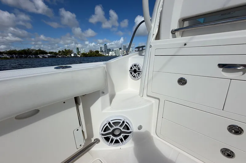 Slide: The Image of 2014 Boston Whaler 315 Conquest boat interior with speakers and storage, city skyline view. - 22