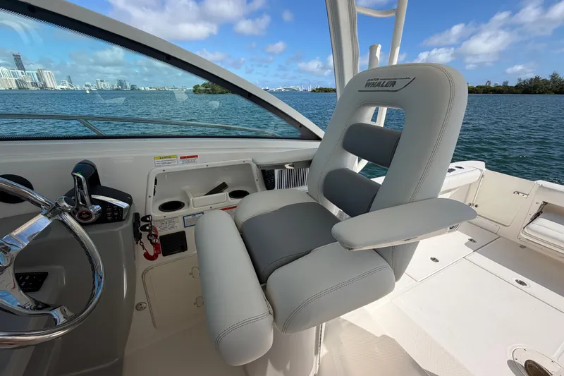 Slide: The Image of 2014 Boston Whaler 315 Conquest helm seat with ocean view and city skyline. - 28