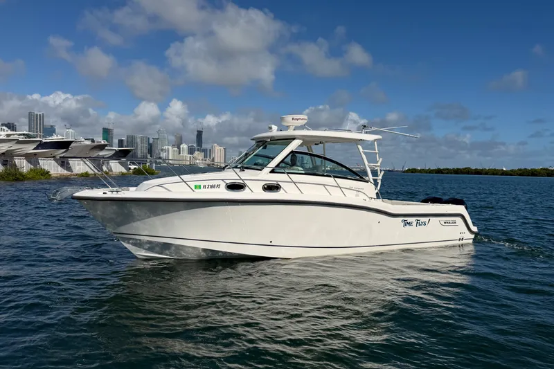 The Image of 2014 Boston Whaler 315 Conquest boat cruising on water with city skyline backdrop. - 0