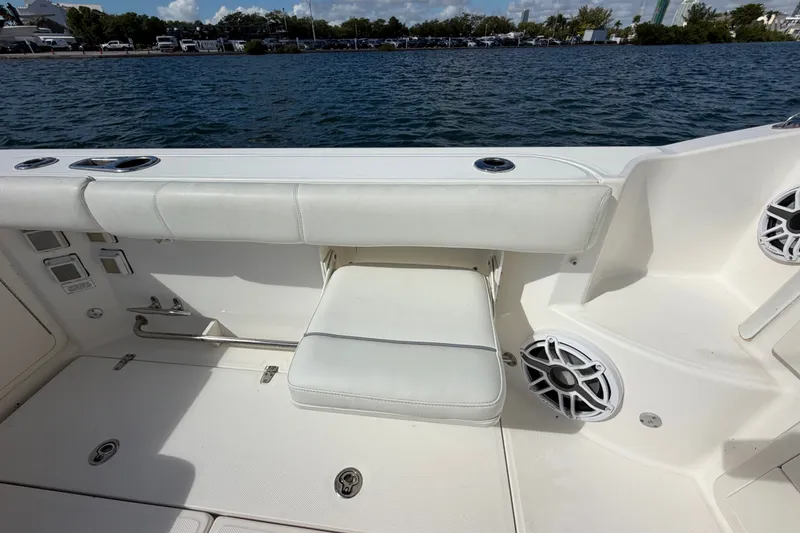 Slide: The Image of 2014 Boston Whaler 315 Conquest boat interior with white seating and speaker by the water. - 23