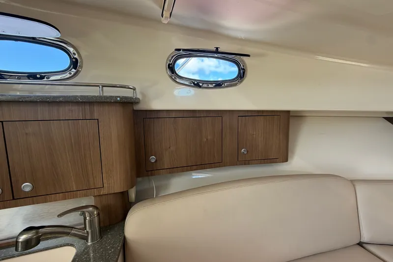 Slide: The Image of Interior of 2014 Boston Whaler 315 Conquest with wooden cabinets and porthole windows. - 48
