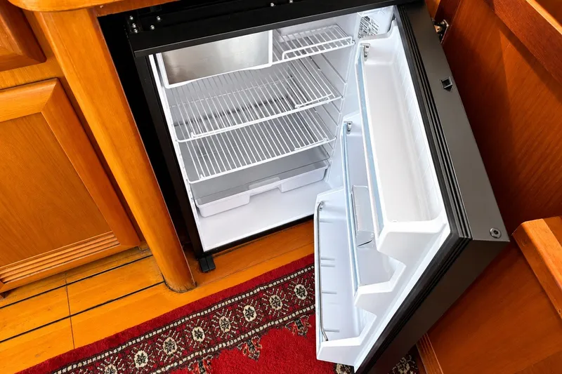 Slide: The Image of Open refrigerator in 2005 Beneteau Swift Trawler 42, showcasing interior shelves and wooden cabinetry. - 15