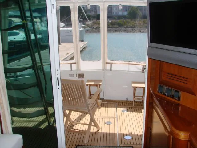 Slide: The Image of Die Beneteau Swift Trawler 42 von 2005 zeigt eine gemütliche Sitzecke mit Holzmöbeln und Blick auf den Hafen. - 38
