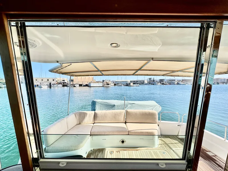 Slide: The Image of View from the salon to the aft deck with beige sofa and harbor in the background. - 12