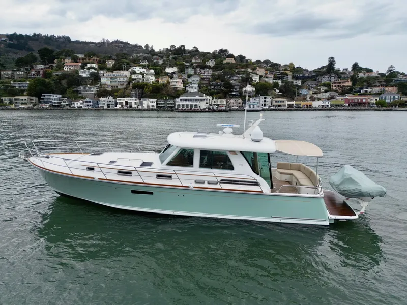 Slide: The Image of 2016 Sabre 48 Salon Express on calm water with a scenic coastal town in the background. - 1