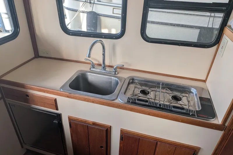 Slide: The Image of Compact kitchen in a 1995 Nordic Tug 26, featuring a sink and two-burner stove. - 15