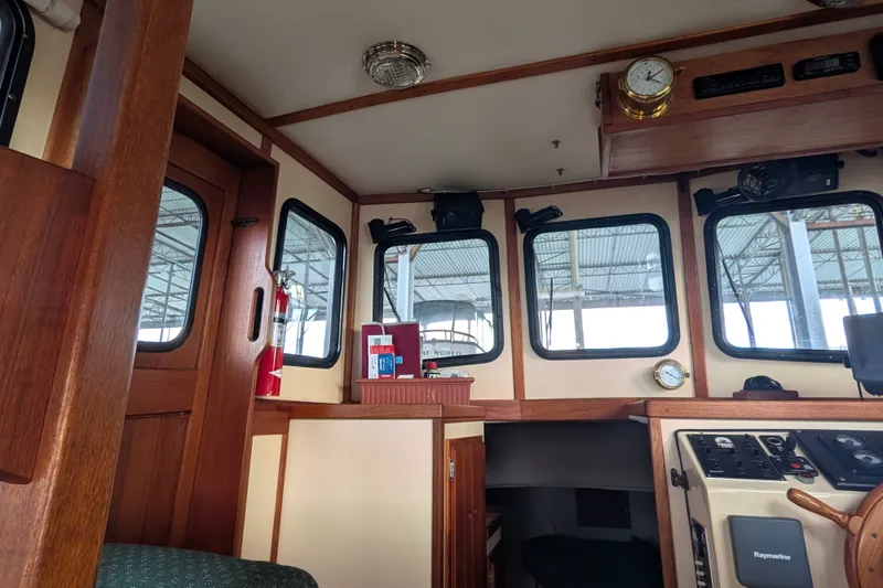 Slide: The Image of Interior of a 1995 Nordic Tug 26 boat, featuring wooden paneling and navigation equipment. - 21