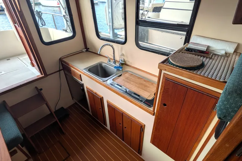 Slide: The Image of Cozy 1995 Nordic Tug 26 interior with wooden cabinetry and compact kitchen area. - 18