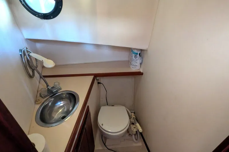 Slide: The Image of Compact bathroom in a 1995 Nordic Tug 26, featuring a sink and toilet. - 32