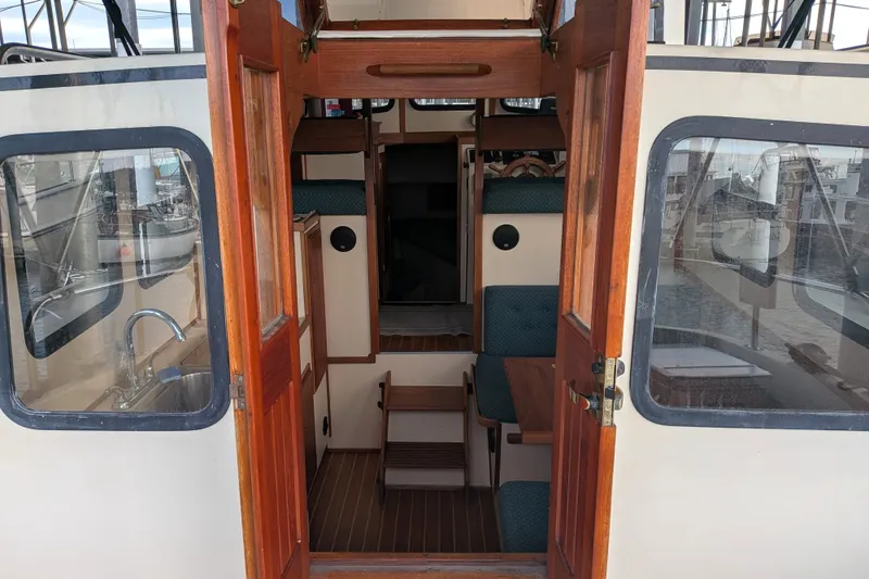 Slide: The Image of Interior view of a 1995 Nordic Tug 26, showcasing wooden doors and seating. - 10