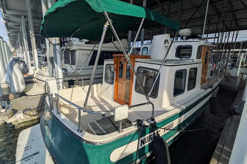 Slide: The Image of 1995 Nordic Tug 26 docked under a covered marina with green canopy. - 7