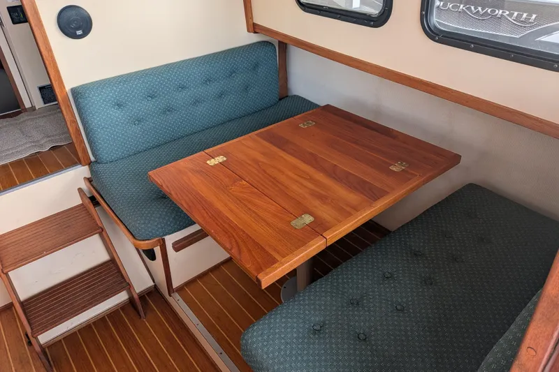 Slide: The Image of Cozy dining area in a 1995 Nordic Tug 26, featuring wooden table and cushioned seating. - 13