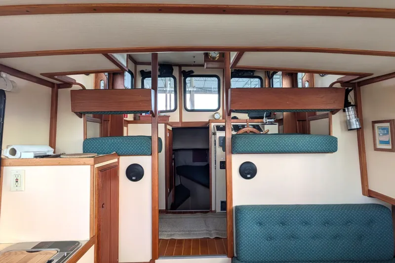 Slide: The Image of Interior of a 1995 Nordic Tug 26 boat, featuring wood accents and green upholstery. - 16