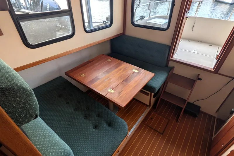 Slide: The Image of Interior of a 1995 Nordic Tug 26 with wooden table and green cushioned seating. - 17