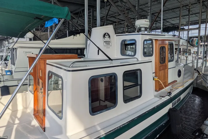 Slide: The Image of 1995 Nordic Tug 26 docked in a marina, showcasing its classic design and wooden accents. - 4