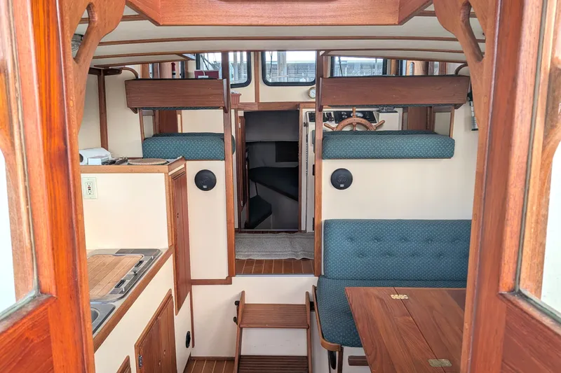Slide: The Image of Interior of a 1995 Nordic Tug 26, featuring wood accents and cozy seating. - 9