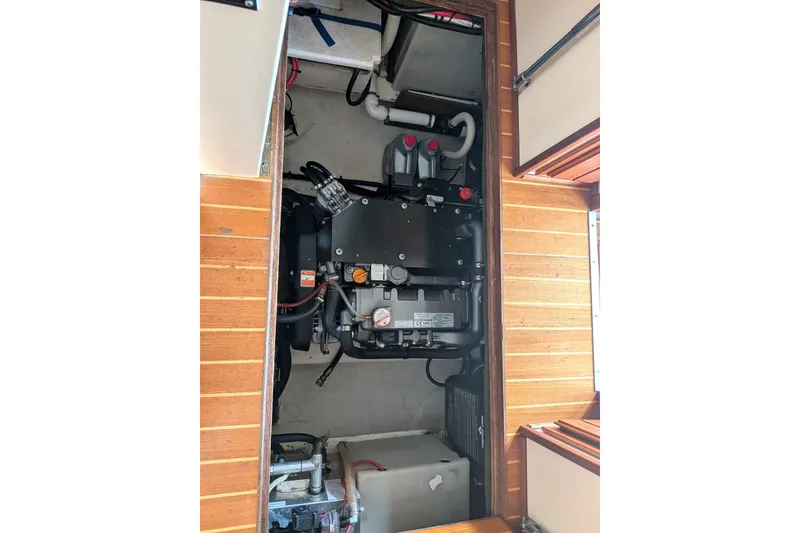 Slide: The Image of Engine compartment of a 1995 Nordic Tug 26, showcasing mechanical components and wooden flooring. - 34