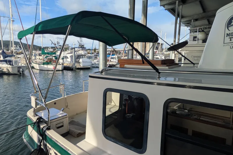 Slide: The Image of 1995 Nordic Tug 26 docked at marina with green canopy and surrounding boats. - 3