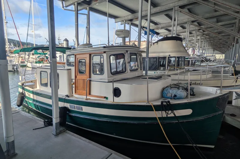 The Image of 1995 Nordic Tug 26 docked in a marina under a covered shelter. - 0