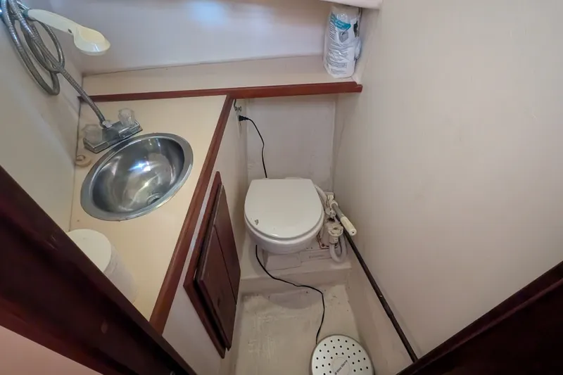 Slide: The Image of 1995 Nordic Tug 26 bathroom with sink, toilet, and showerhead in compact space. - 33