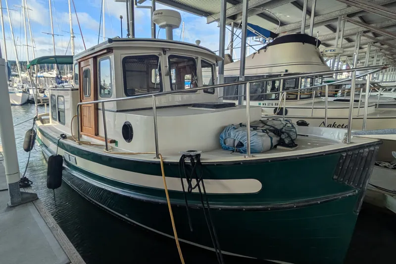 Slide: The Image of 1995 Nordic Tug 26 docked in a marina, featuring a green hull and classic design. - 1