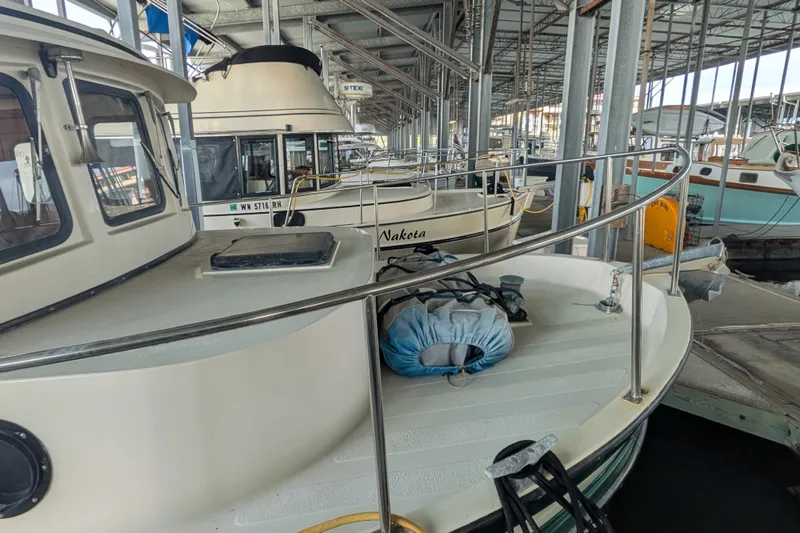 Slide: The Image of 1995 Nordic Tug 26 docked in a marina, showcasing its classic design and sturdy build. - 2