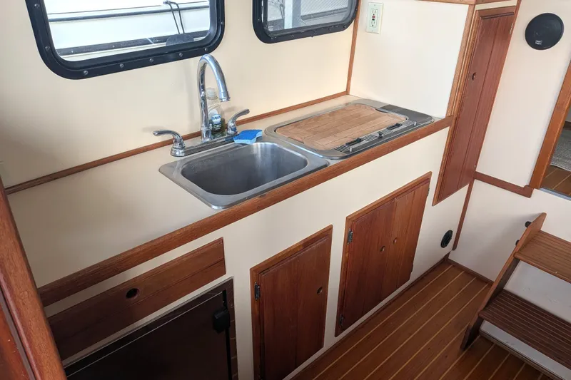 Slide: The Image of 1995 Nordic Tug 26 interior kitchen with sink, stove, and wooden cabinetry. - 14