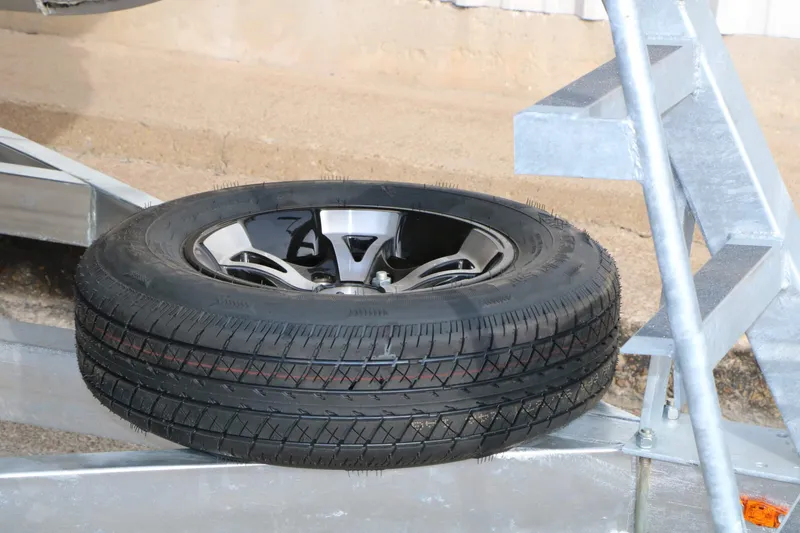 Slide: The Image of Spare tire mounted on a boat trailer, featuring a metal frame and sandy background. - 28