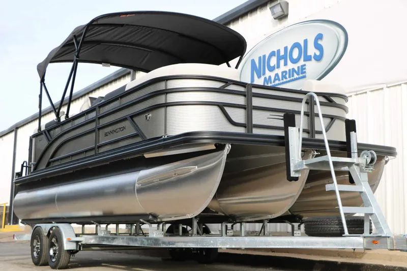 Slide: The Image of Bennington 22 S1SSR Tri Toon 2027 on a trailer with a sunshade, parked in front of a building. - 15