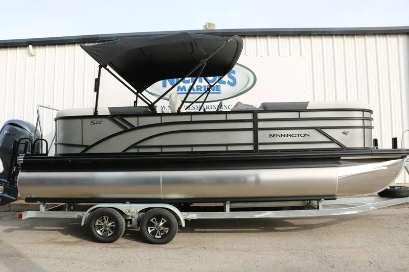 Slide: The Image of 2027 Bennington 22 S1SSR Tri Toon on a trailer in front of a building. - 2