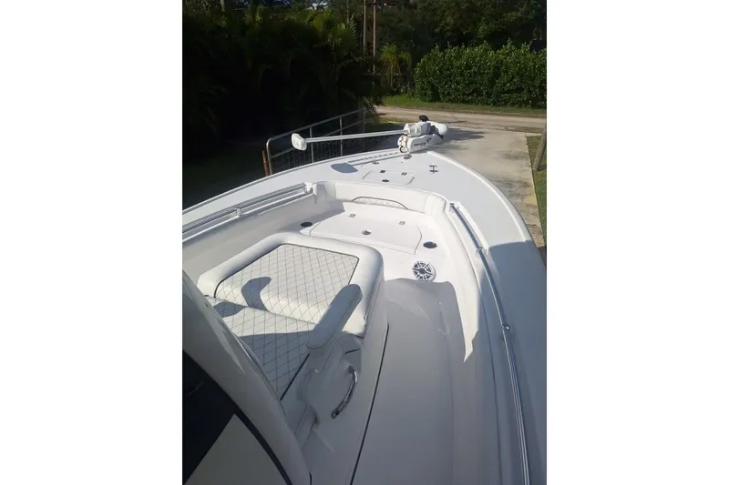 Slide: The Image of 2022 Sportsman Masters 247OE Bay Boat, white deck, cushioned seating, outdoor setting. - 8