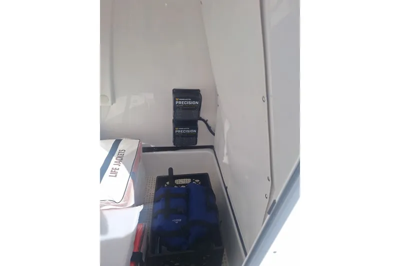 Slide: The Image of Storage compartment in 2022 Sportsman Masters 247OE Bay Boat with life jackets and charger. - 11
