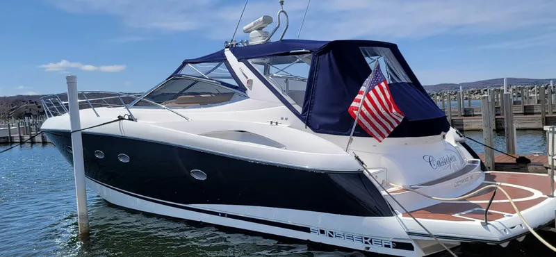 Slide: The Image of A 2006 Sunseeker Portofino 46 docked. It features a blue canopy and an American flag. - 6