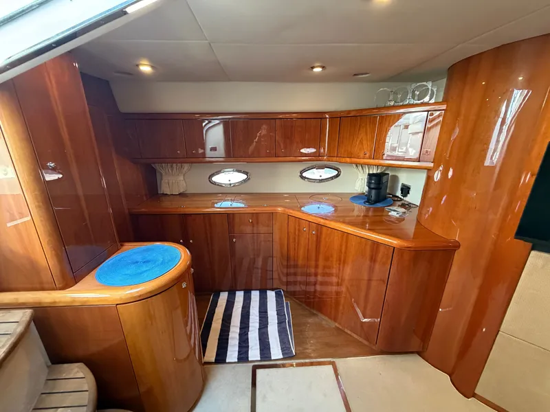Slide: The Image of The interior cabin of a 2006 Sunseeker Portofino 46 with glossy wood cabinetry and round windows. - 17