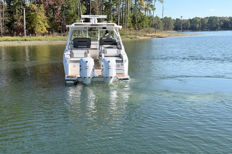 Slide: The Image of 2020 Tiara Sport 34 LX boat cruising on a serene lake with forested shoreline. - 4