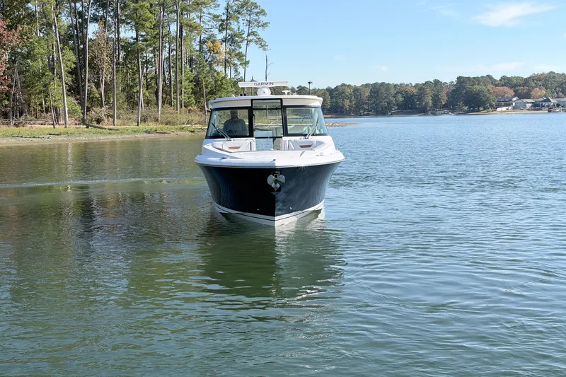 Slide: The Image of 2020 Tiara Sport 34 LX boat cruising on a serene lake with forested shoreline. - 7