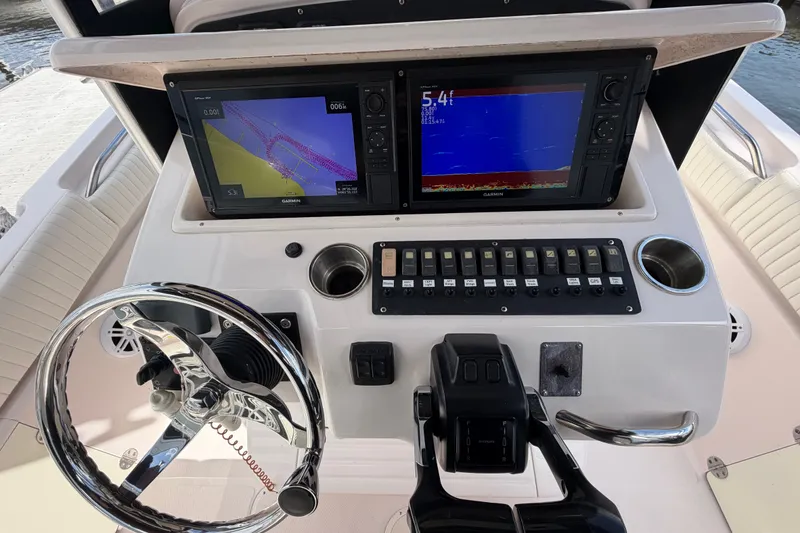 Slide: The Image of Grady-White Release 283 boat dashboard with Garmin navigation displays, steering wheel, and control panel. - 13