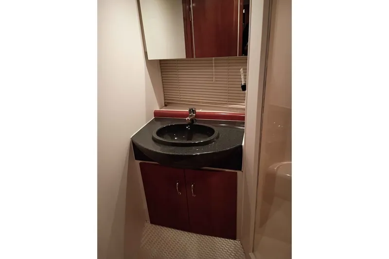 Slide: The Image of Bathroom sink area in 2003 Carver 350 Mariner yacht, featuring dark countertop and wooden cabinetry. - 11