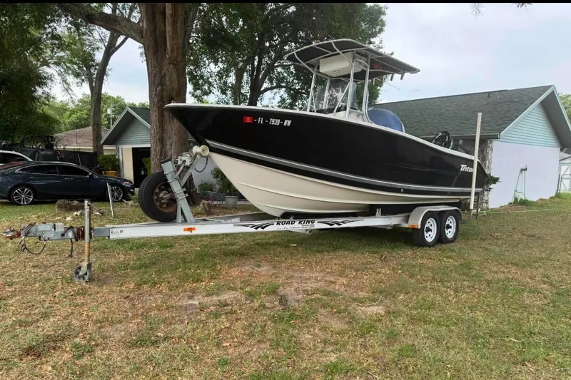 Slide: The Image of 2008 Triton 225 CC boat on trailer, parked in a yard near a house. - 5