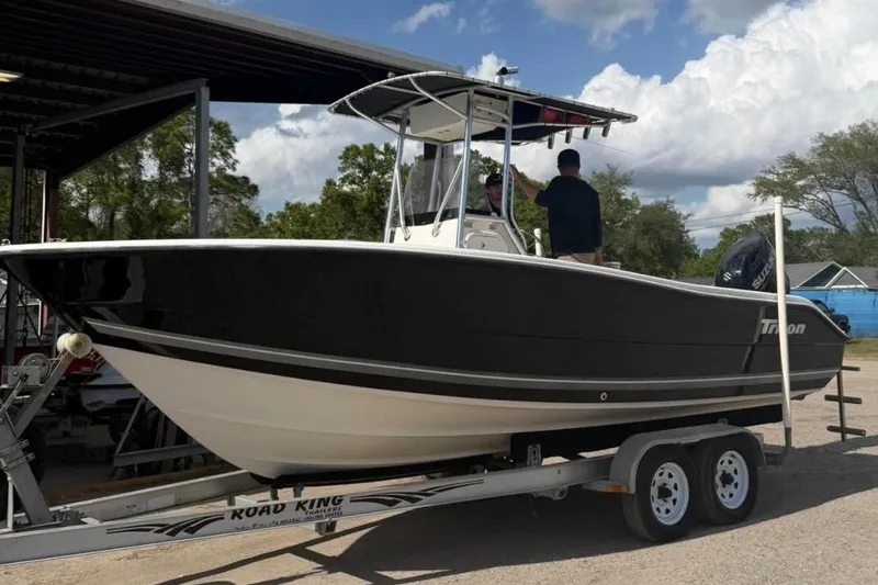 Slide: The Image of 2008 Triton 225 CC boat on trailer, parked outdoors under a cloudy sky. - 1