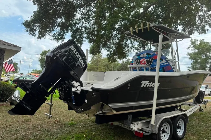 Slide: The Image of 2008 Triton 225 CC boat on trailer with Suzuki outboard motor, parked outdoors. - 4