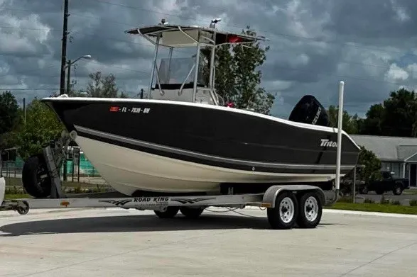 Slide: The Image of 2008 Triton 225 CC boat on a trailer, parked outdoors under cloudy skies. - 2