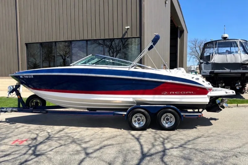 Slide: The Image of 2017 Regal 2300 Bowrider boat on trailer, parked outside a building. - 1