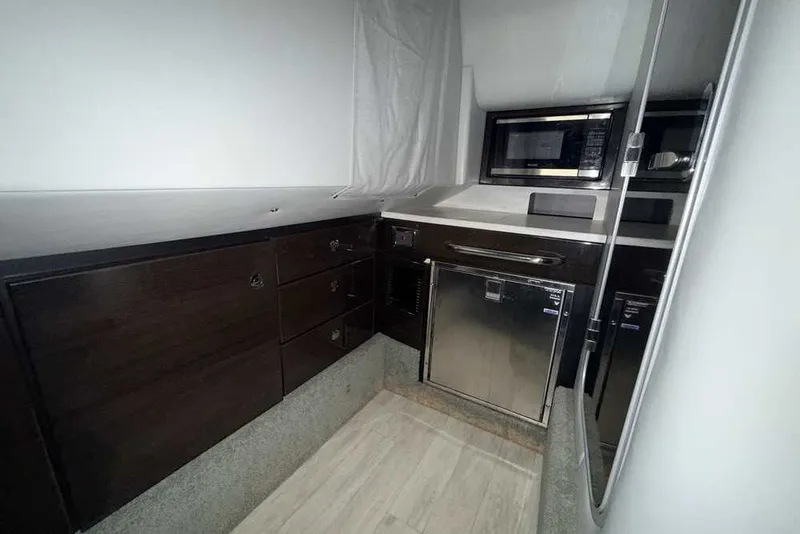 Slide: The Image of 2019 Formula 350 Crossover Bowrider I/O interior with kitchenette, featuring microwave and storage cabinets. - 34