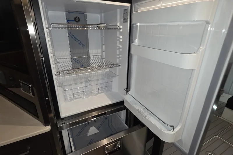 Slide: The Image of Open refrigerator inside a 2018 Carver C52 Coupe yacht, showcasing shelves and storage compartments. - 16